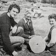 Mr. Brian Williams (left) of the Historic Monuments and Buildings branch of the Department of the Environment, explaining the history of the quern stone before him to Mr. James Armstrong and his wife, Ivy, after it was found during a dig in a fort on