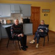 Brendan and Anne in their kitchen on garden chairs.