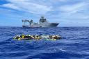 A shipment of cocaine floats on the surface of the Pacific Ocean with Royal New Zealand Navy vessel HMNZS Manawanui behind