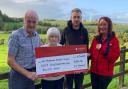 Harold and Joan Williamson, from Fivemiletown, pictured with their son, Lyle, presenting £810 to Air Ambulance Northern Ireland volunteer Hazel McClelland.
