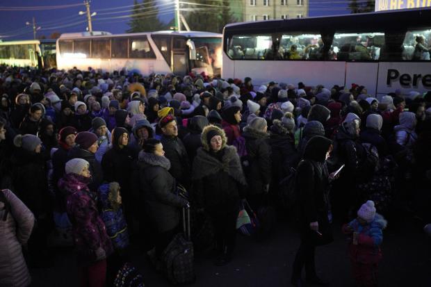 Refugees fleeing the war in Ukraine, form a line as they approach the border with Poland in Shehyni, Ukraine on Sunday.  AP Photo/Daniel Cole)