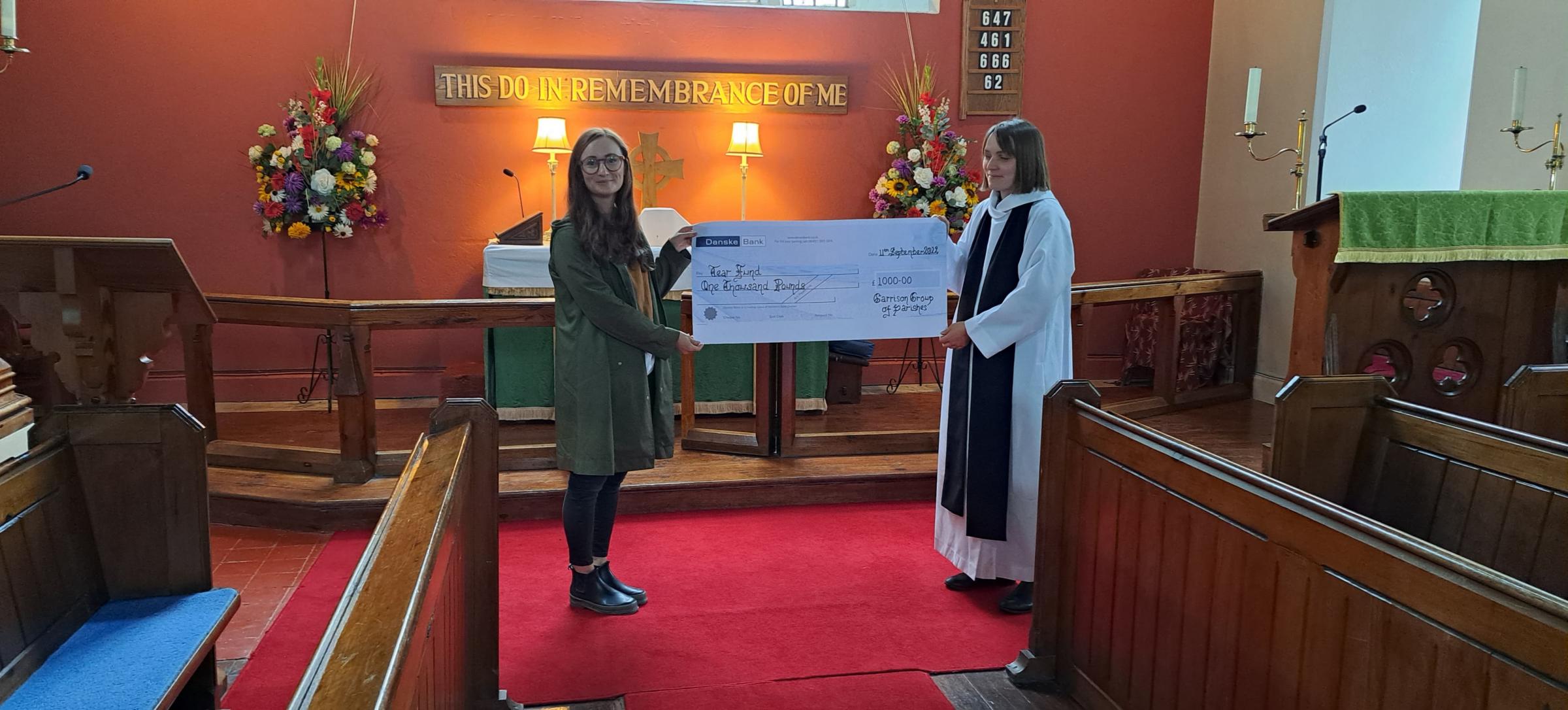 Reverend Rebecca Guildea presenting a cheque with money raised to a representative of Tearfund.