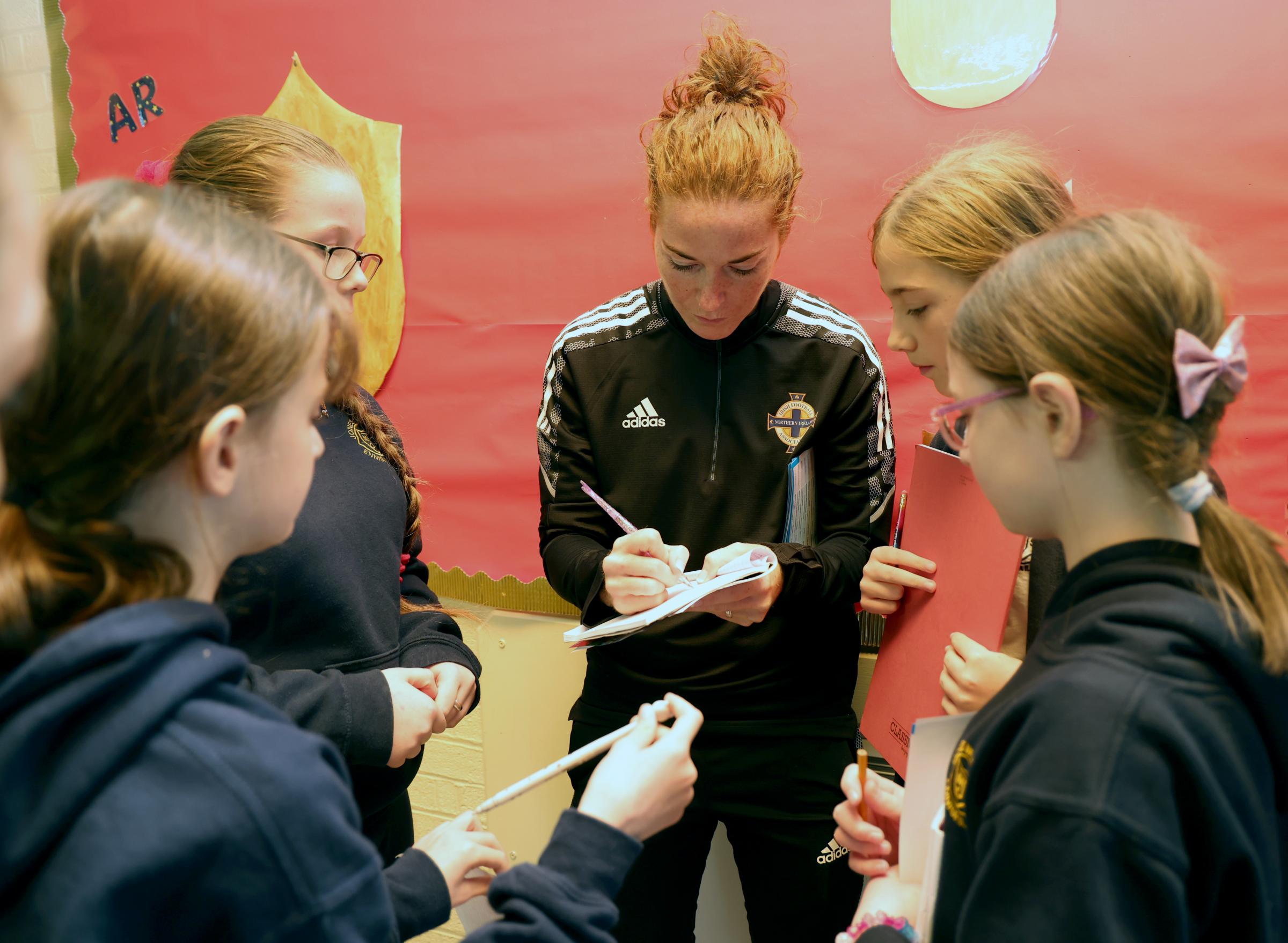 Marissa Callaghan, Northern Ireland Captain and IFA Diversification Officer, signing autographs fro pupils at Jones Memorial Primary School.