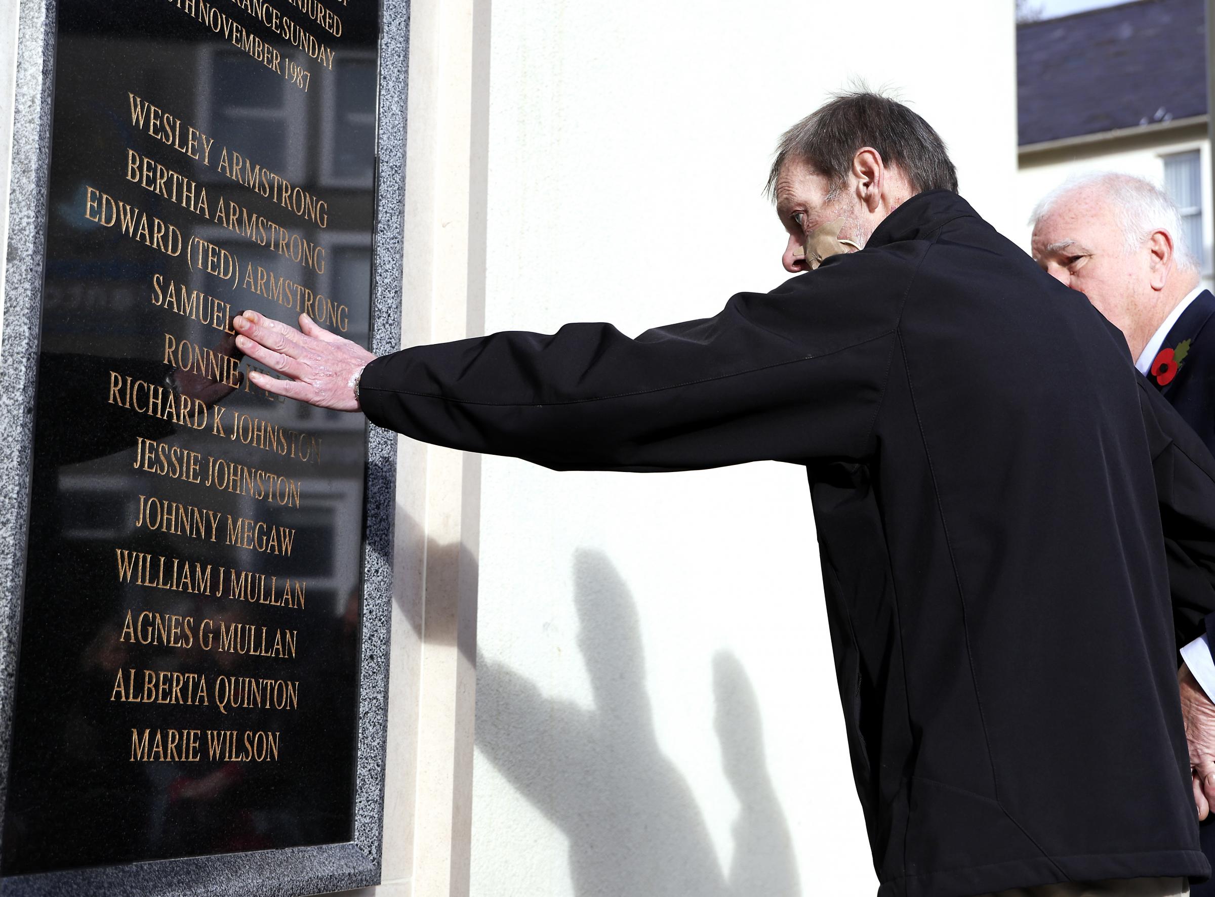 Keith Gault, touches the name of his father Samuel who was killed in The Enniskillen Bomb after lawing flowers during the service.
