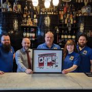 James Eames, Mark Edwards (General Manager of Blake's of the Hollow), Paul Trimble, Lauren Trimble and Stephen Trimble with a special 'Dennis the Menace' picture presentation to the bar for its greatly appreciated role in the town's